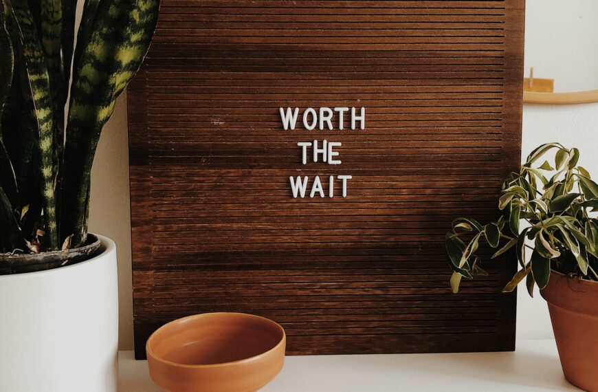 white Worth The Wait sign on brown wooden board